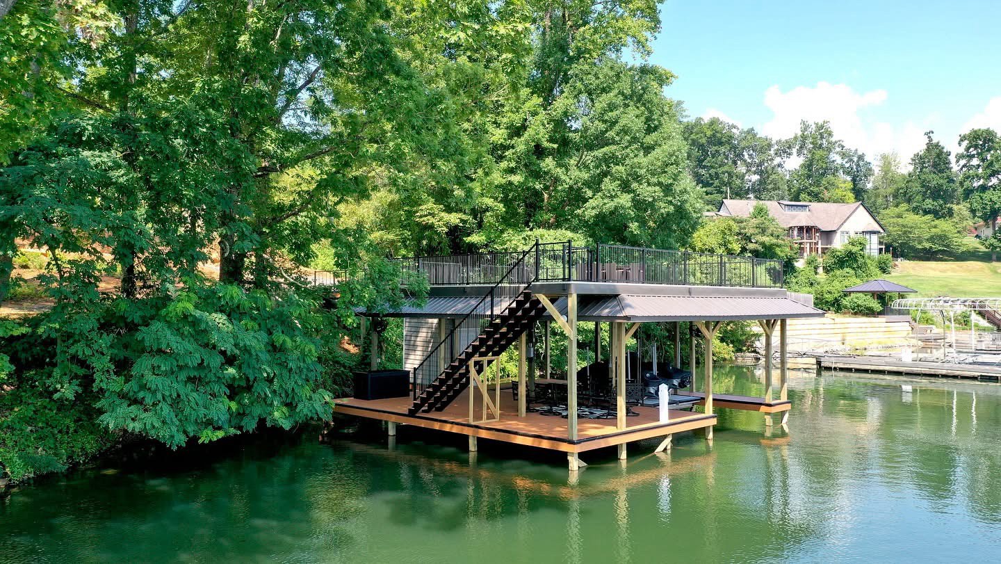 Two-story covered boat dock with rooftop deck on a wooded Tennessee lake